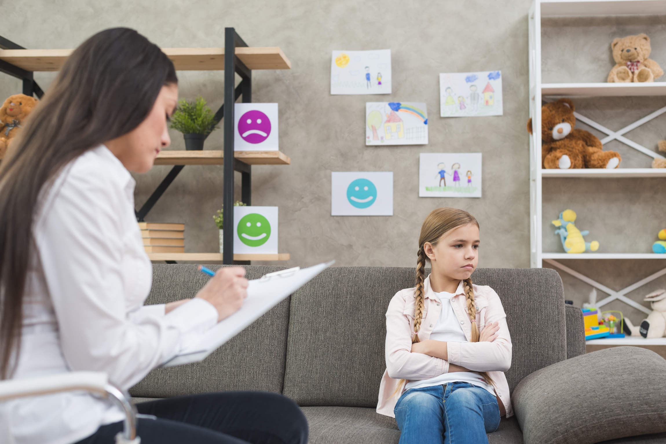 depressed girl sitting sofa with female psychologist writing note clipboard 1